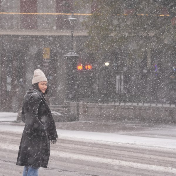 A person walks to Jackson Square as snow falls in the French Quarter in New Orleans, Tuesday, Jan. 21, 2025. (AP Photo/Gerald Herbert)