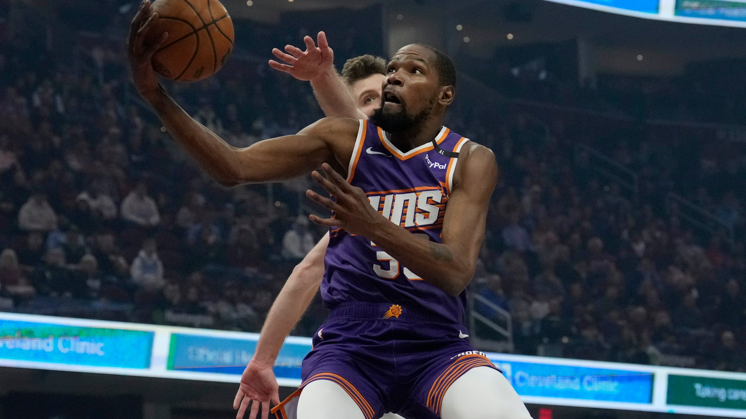 Phoenix Suns forward Kevin Durant, front, goes to the basket past Cleveland Cavaliers forward Dean Wade, back, in the first half of an NBA basketball game, Monday, Jan. 20, 2025, in Cleveland. (AP Photo/Sue Ogrocki)