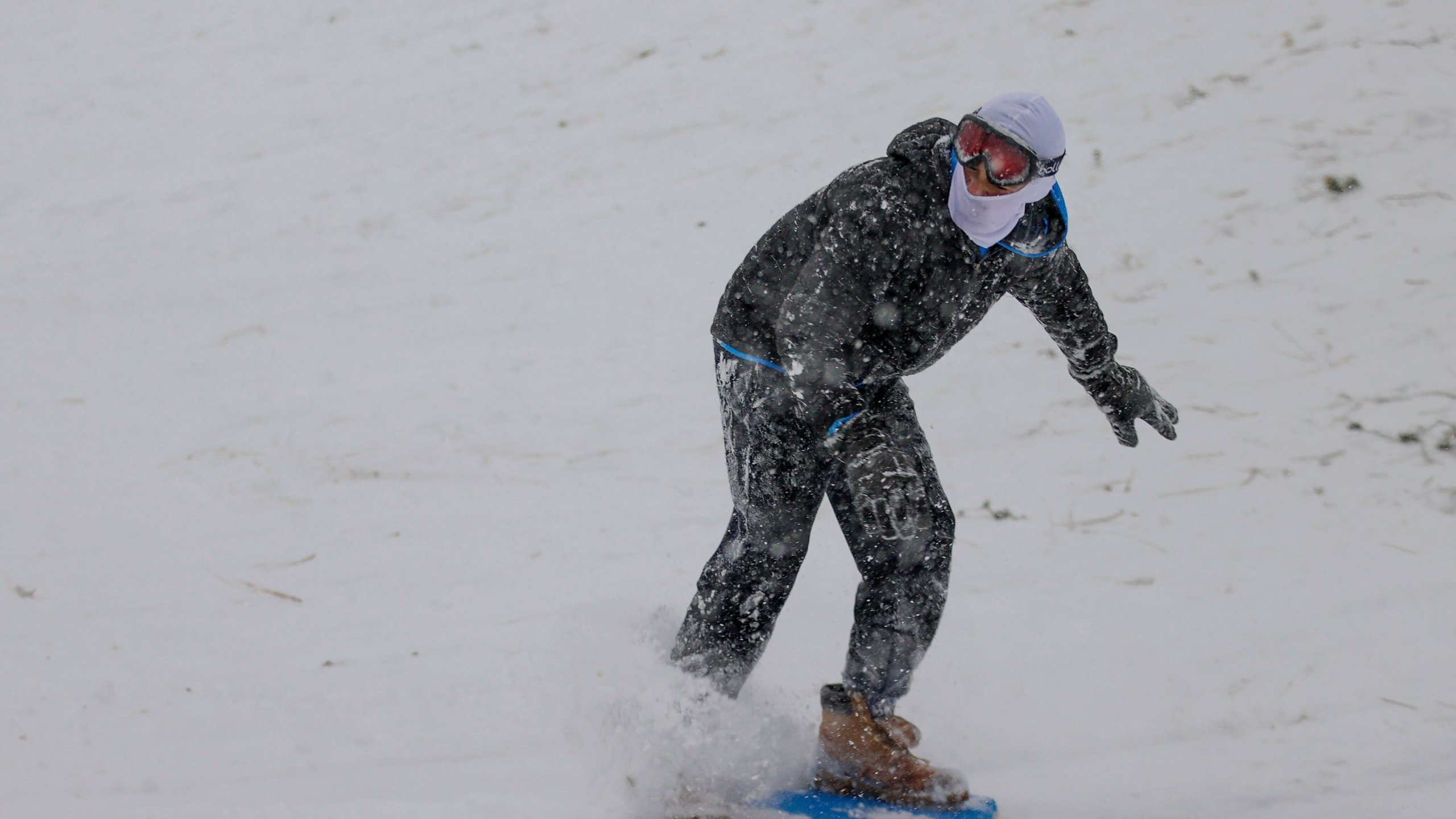 Matthey Shashaty, 12, uses a skim board snow at Bayview Park on Tuesday, Jan. 21, 2025, in Pensacola, Fla. (Luis Santana/Tampa Bay Times via AP)