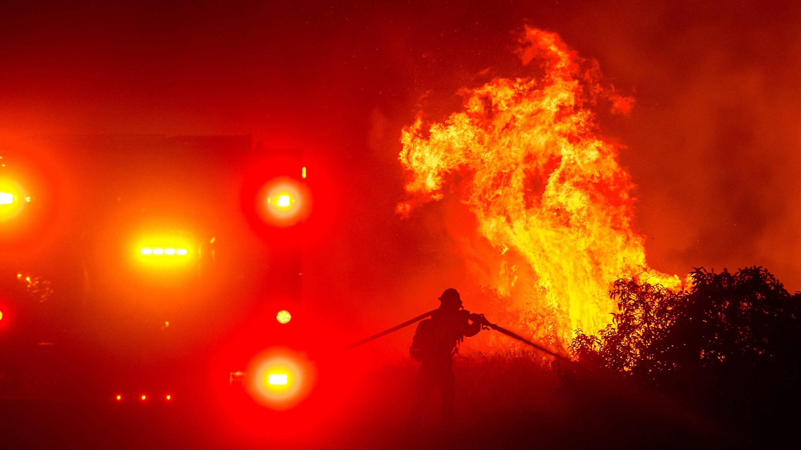 A firefighter sprays water while battling the Lilac Fire near the Bonsall community of San Diego County, Calif., on Tuesday, Jan. 21, 2025. (AP Photo/Noah Berger)