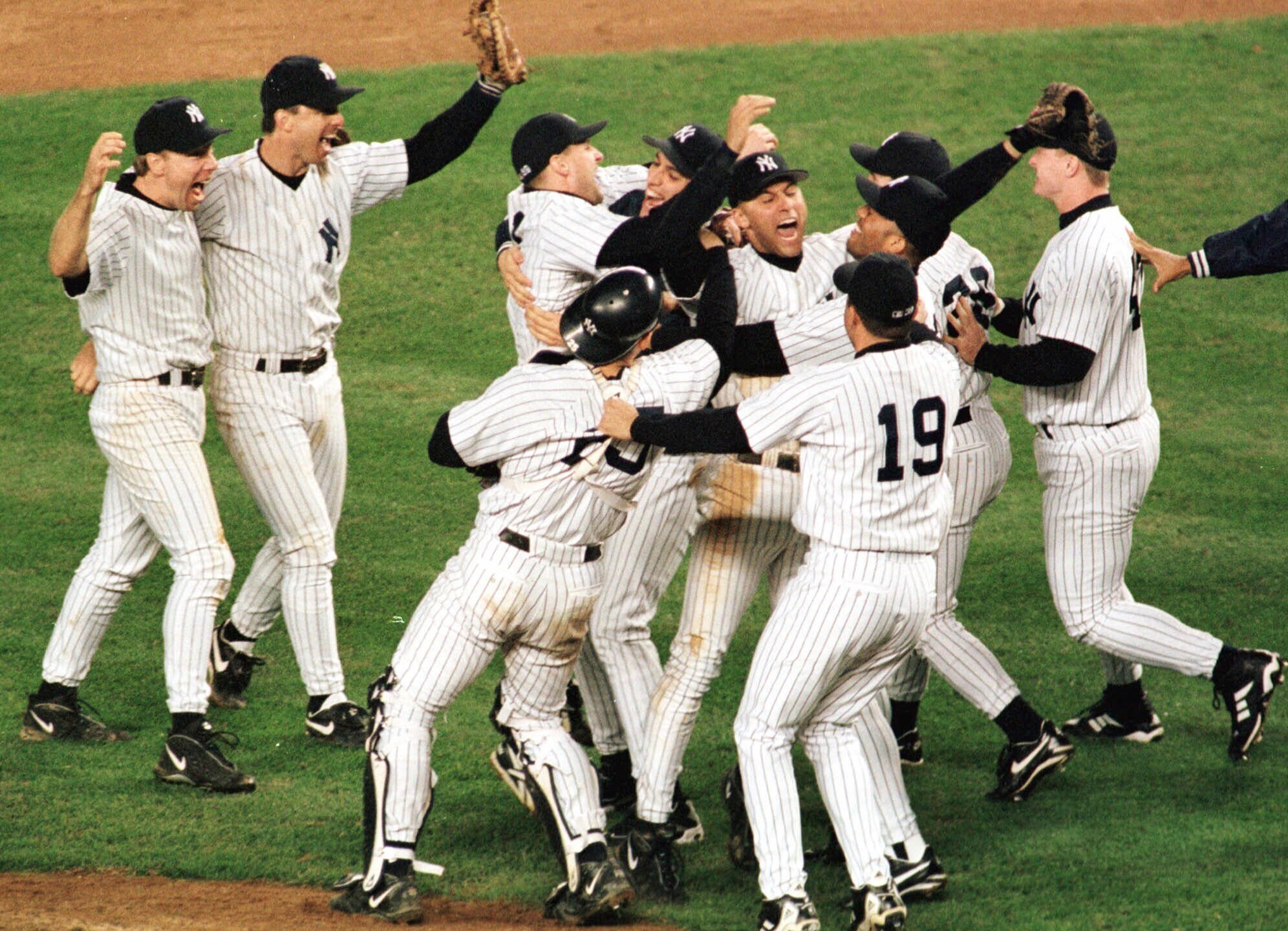 FILE - New York Yankees Derek Jeter is surrounded by teammates as they celebrate after defeating the Cleveland Indians 9-5 in Game 6 of the American League Championship Series Tuesday, Oct. 13, 1998 at Yankee Stadium in New York. (AP Photo/John Dunn, File)