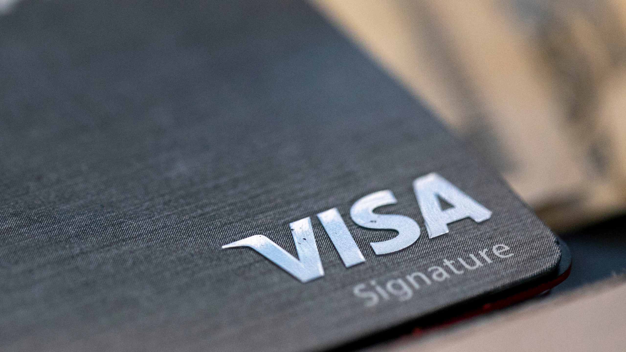 FILE- This photo shows a Visa logo on a credit card in New Orleans, Aug. 11, 2019. (AP Photo/Jenny Kane, File)