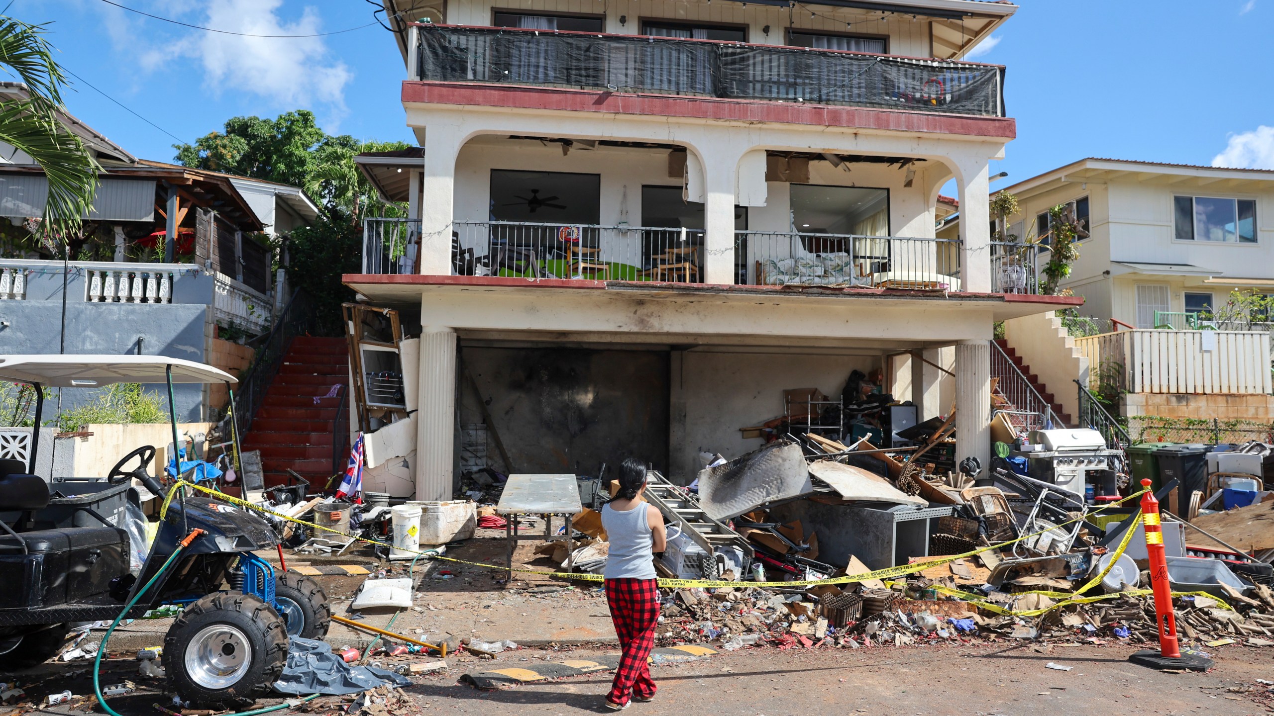 FILE - A woman stands in front of the home where a New Year's Eve fireworks explosion killed and injured people, Jan. 1, 2025, in Honolulu. (AP Photo/Marco Garcia, file)