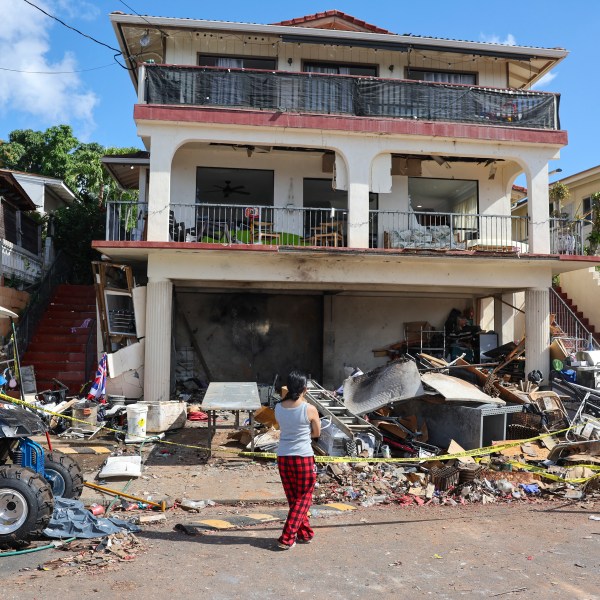 FILE - A woman stands in front of the home where a New Year's Eve fireworks explosion killed and injured people, Jan. 1, 2025, in Honolulu. (AP Photo/Marco Garcia, file)