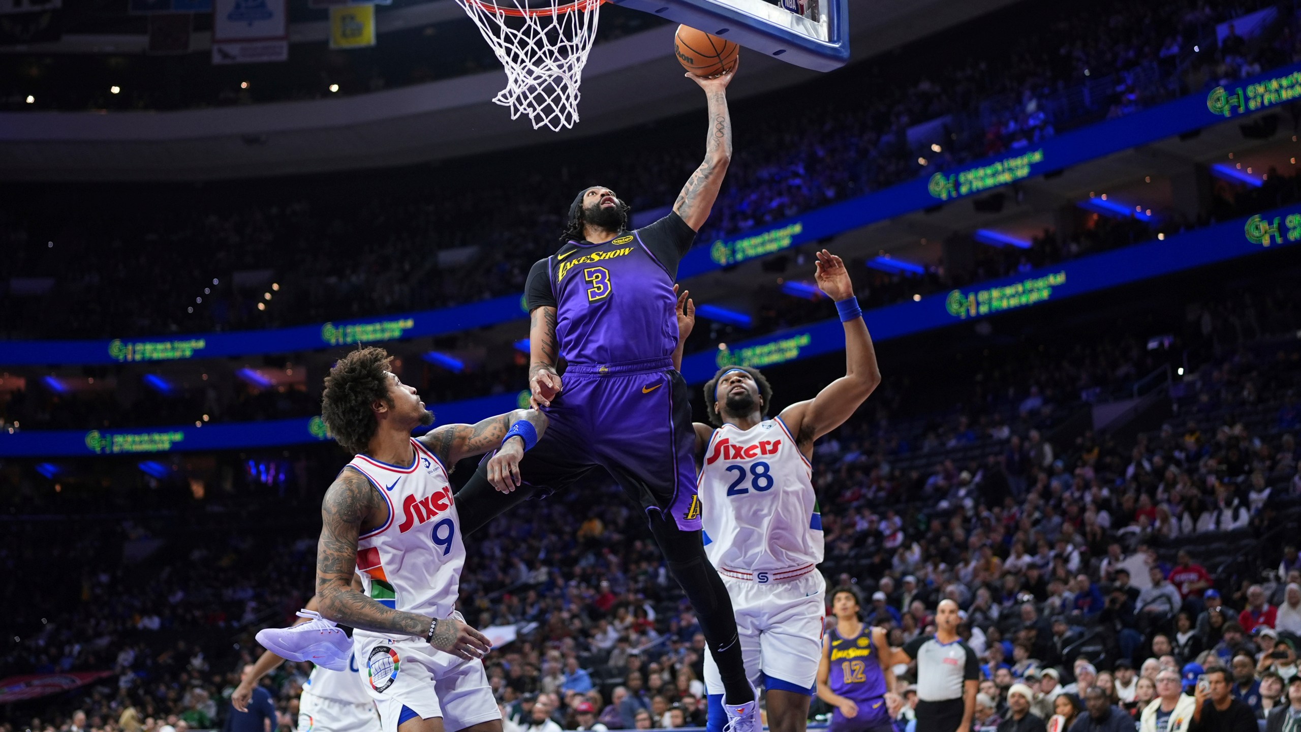 Los Angeles Lakers' Anthony Davis (3) goes up for a shot against Philadelphia 76ers' Guerschon Yabusele (28) and Kelly Oubre Jr. (9) during the first half of an NBA basketball game, Tuesday, Jan. 28, 2025, in Philadelphia. (AP Photo/Matt Slocum)