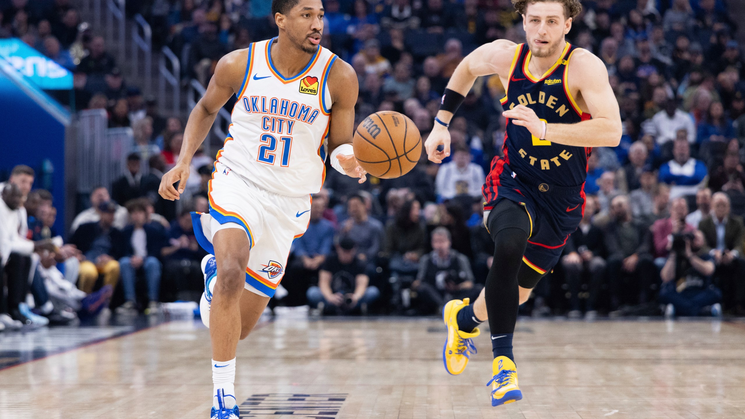 Oklahoma City Thunder guard Aaron Wiggins (21) dribbles past Golden State Warriors guard Brandin Podziemski during the first half of an NBA basketball game Wednesday, Jan. 29, 2025, in San Francisco. (AP Photo/Benjamin Fanjoy)