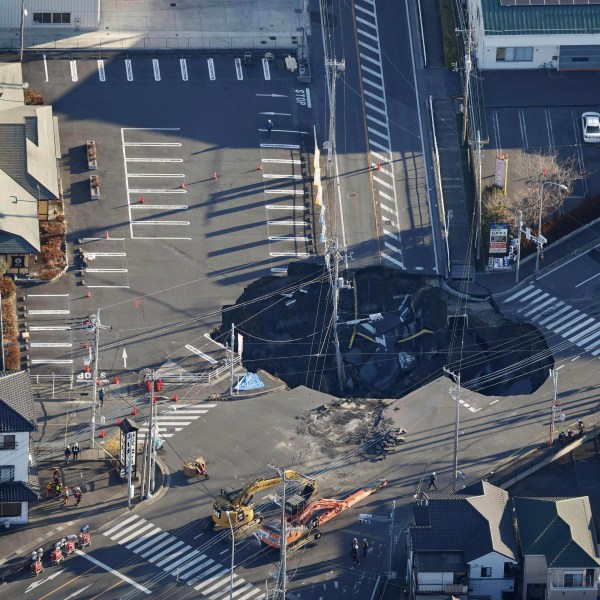 Police officers and rescue members prepare for a rescue mission in Yashio, northeast of Tokyo, Thursday, Jan. 30, 2025, two days after a truck fell into the sinkhole made on a street Tuesday. (Yu Matsuda/Kyodo News via AP)