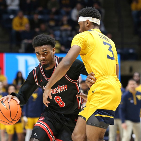 Houston guard Mylik Wilson (8) is defended by West Virginia guard KJ Tenner (3) during the second half of an NCAA college basketball game, Wednesday, Jan. 29, 2025, in Morgantown, W.Va. (AP Photo/Kathleen Batten)