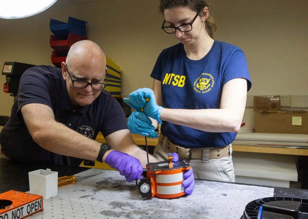 National Transportation Safety Board (NTSB) investigators examine cockpit voice recorder and flight data recorder recovered from the American Airlines passenger jet that crashed with an Army helicopter Wednesday night near Washington, D.C, Thursday, Jan.30, 2024. (NTSB via AP)