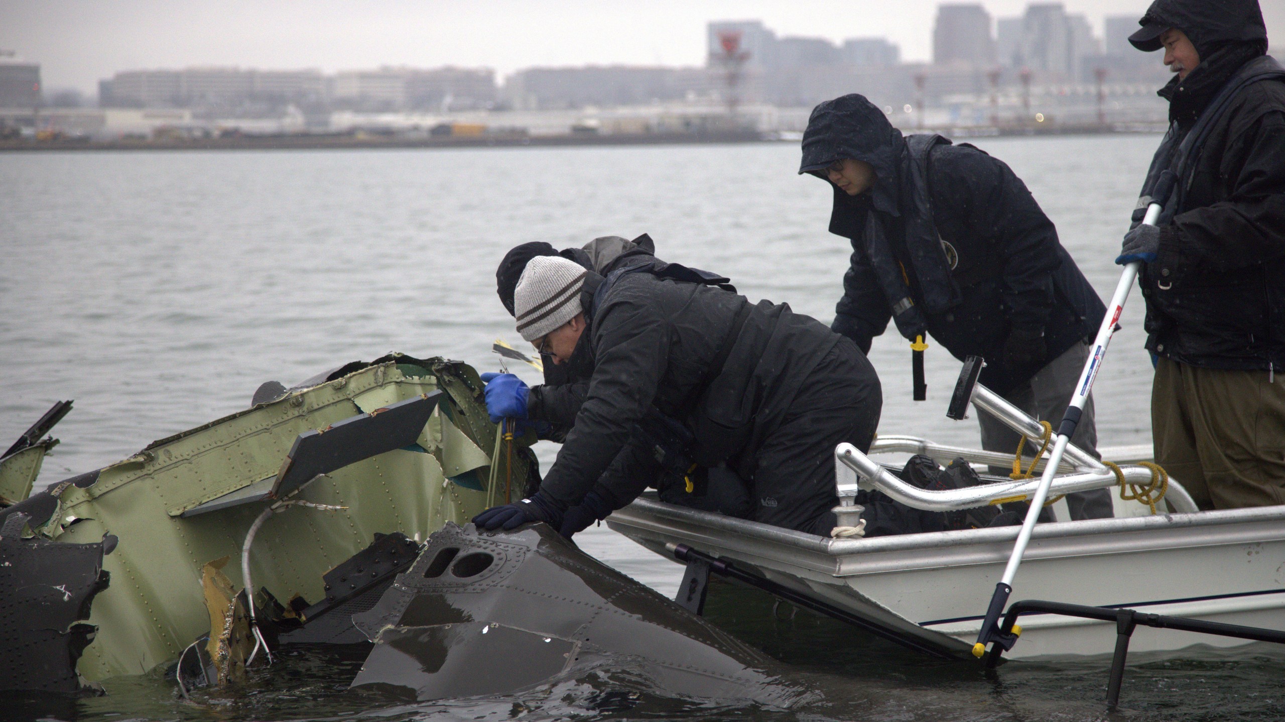 In this undated image provided by the National Transportation Safety Board, NTSB investigators and members of the salvage crew recover wreckage from the Army Black Hawk helicopter that collided with an American Airlines jet Wednesday night, Jan. 29, 2025, near Ronald Reagan Washington National Airport in Arlington, Va. (NTSB via AP)