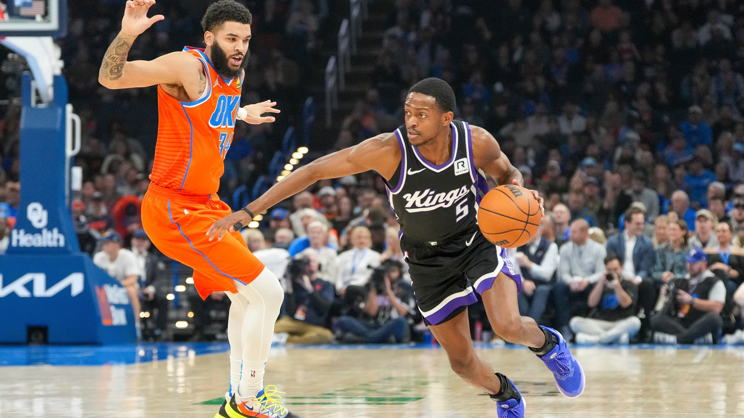 Sacramento Kings guard De'Aaron Fox, right, drives past Oklahoma City Thunder forward Kenrich Williams, left, during the first half of an NBA basketball game, Saturday, Feb. 1, 2025, in Oklahoma City. (AP Photo/Kyle Phillips)