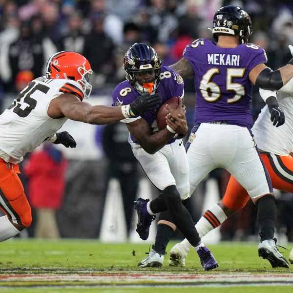 Baltimore Ravens quarterback Lamar Jackson (8) runs with the ball as Cleveland Browns defensive end Myles Garrett, left, defends during the first half of an NFL football game Saturday, Jan. 4, 2025, in Baltimore. (AP Photo/Stephanie Scarbrough)