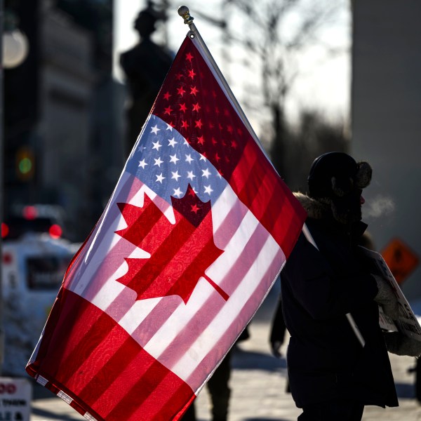 A protester holds the flags of Canada and the United States outside on Parliament Hill in Ottawa, on Saturday, Feb. 1, 2025. (Justin Tang/The Canadian Press via AP)