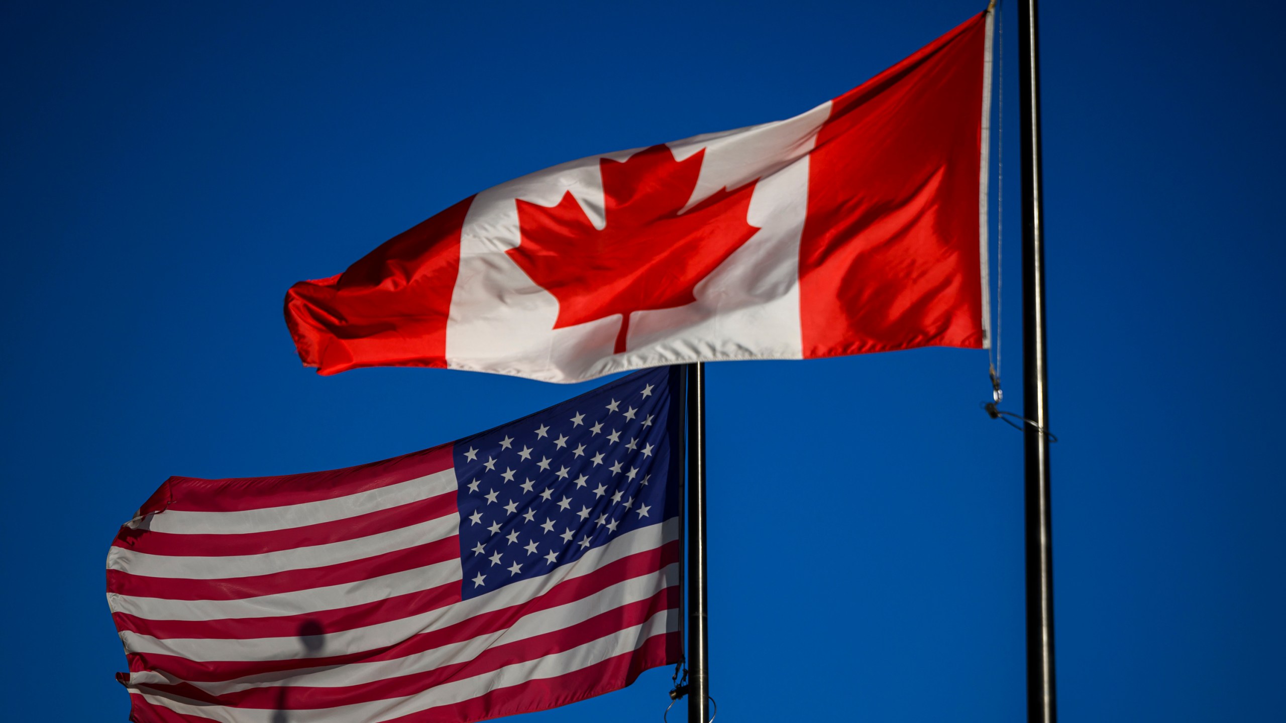 The flags of Canada and the United States fly outside a hotel in downtown Ottawa, on Saturday, Feb. 1, 2025. (Justin Tang/The Canadian Press via AP)