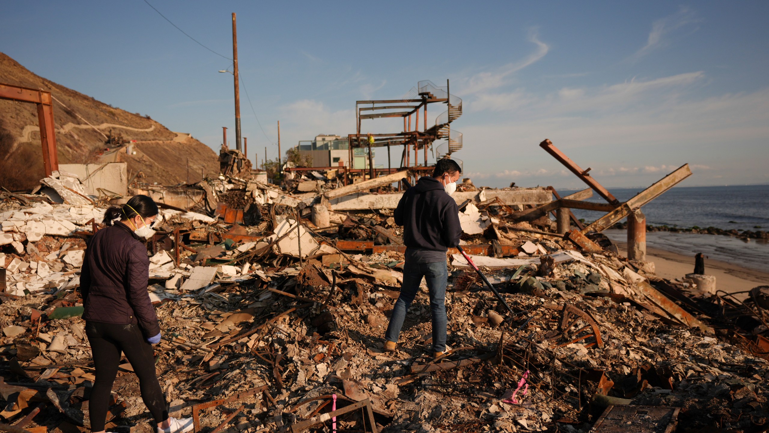 FILE - Tony Lai, center, rakes through the remains of his fire-ravaged beachfront property with his wife Everlyn in the aftermath of the Palisades Fire Tuesday, Jan. 28, 2025 in Malibu, Calif. (AP Photo/Jae C. Hong, File)