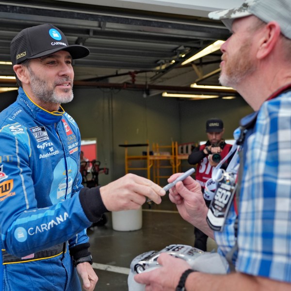 Jimmie Johnson, left, talks to a fan after signing an autograph before a practice for the NASCAR Daytona 500 auto race Friday, Feb. 14, 2025, at Daytona International Speedway in Daytona Beach, Fla. (AP Photo/Chris O'Meara)