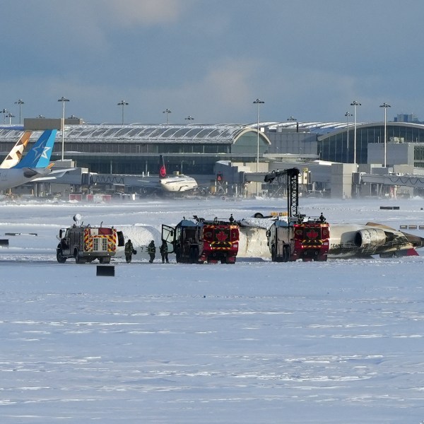 Pearson International Airport firefighters work on an upside down Delta Air Lines plane, which was heading from Minneapolis to Toronto when it crashed on the runway, in Toronto, Monday, Feb. 17, 2025. (Teresa Barbieri/The Canadian Press via AP)