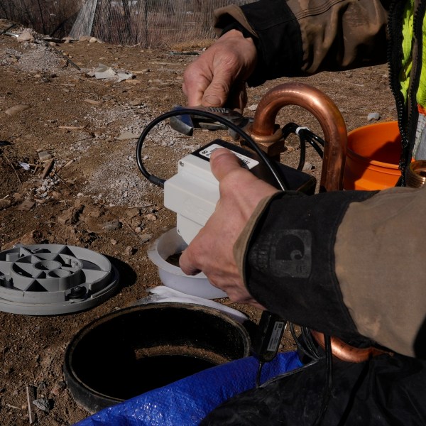 A technician installs a new water meter with a remote shutoff valve Thursday, Feb. 13, 2025, in Louisville, Colo. (AP Photo/Brittany Peterson)