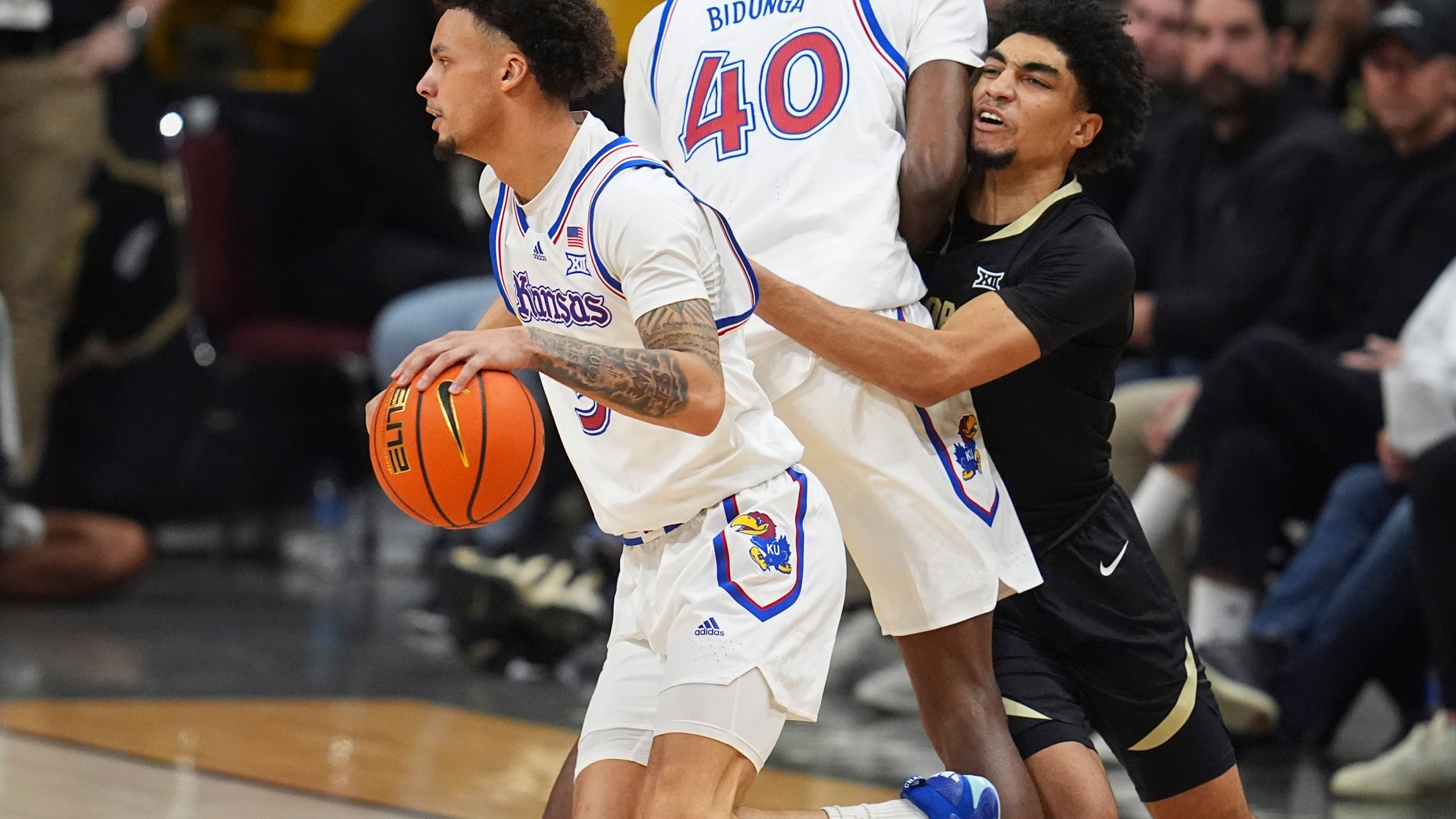 Kansas guard Zeke Mayo, left, drives past forward Flory Bidunga (40) as he blocks Colorado guard RJ Smith in the second half of an NCAA college basketball game Monday, Feb. 24, 2025, in Boulder, Colo. (AP Photo/David Zalubowski)