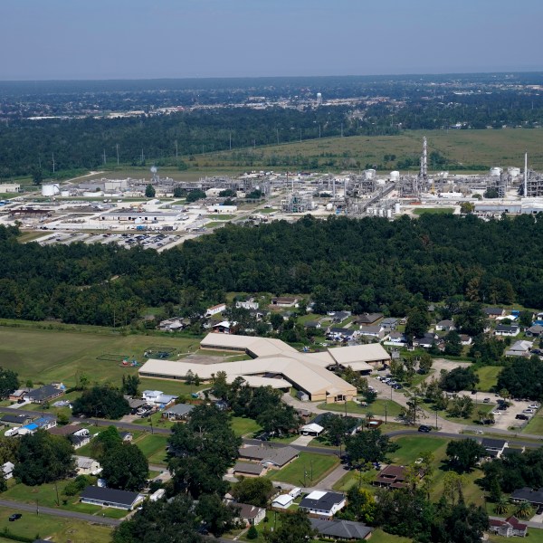 FILE - The Fifth Ward Elementary School and residential neighborhoods sit near the Denka Performance Elastomer Plant, back, in Reserve, La., Sept. 23, 2022. (AP Photo/Gerald Herbert, File)